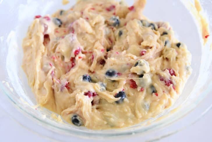 Glass bowl with cake batter with fresh berries mixed in.