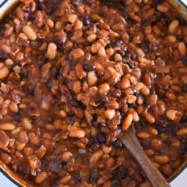 Wooden spoon scooping up calico baked beans.