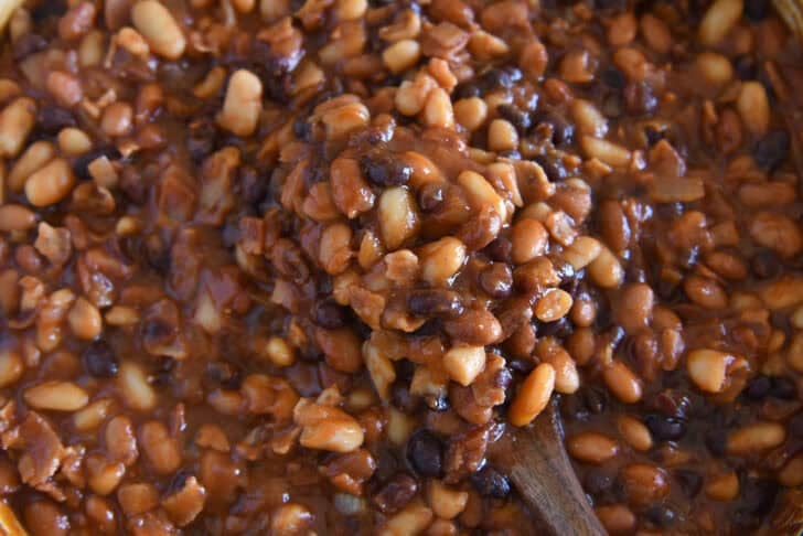 Wooden spoon scooping up calico baked beans.