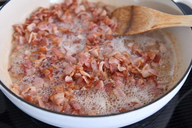 Chopped bacon cooking in pan.