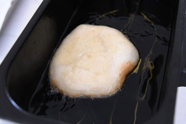 Piece of fry bread dough in electric oil fryer.