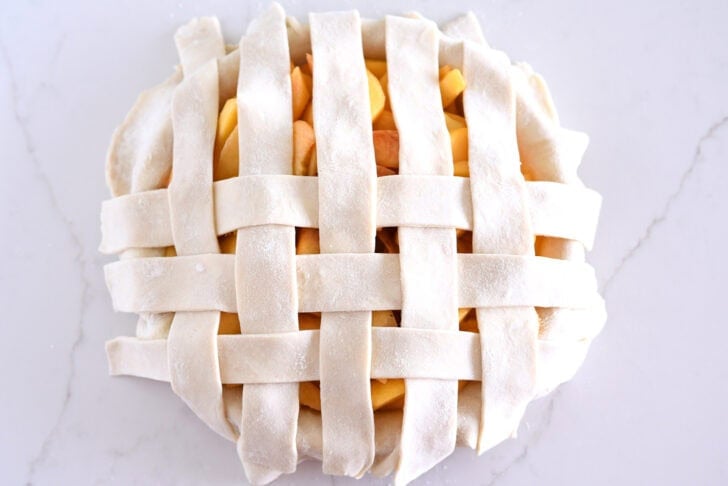 Assembling lattice pie crust on fresh peach pie.