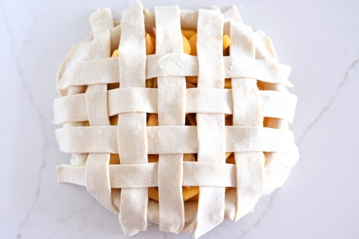 Assembling lattice pie crust on fresh peach pie.