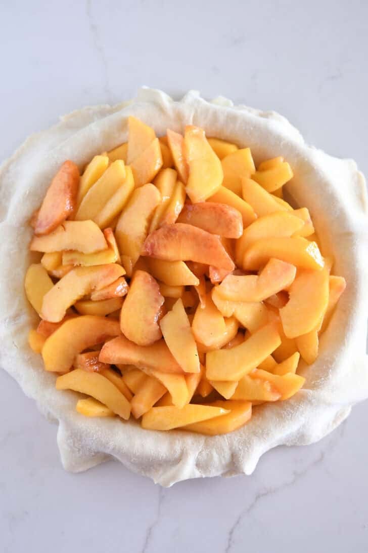 Fresh peach pie filling in pie crust.