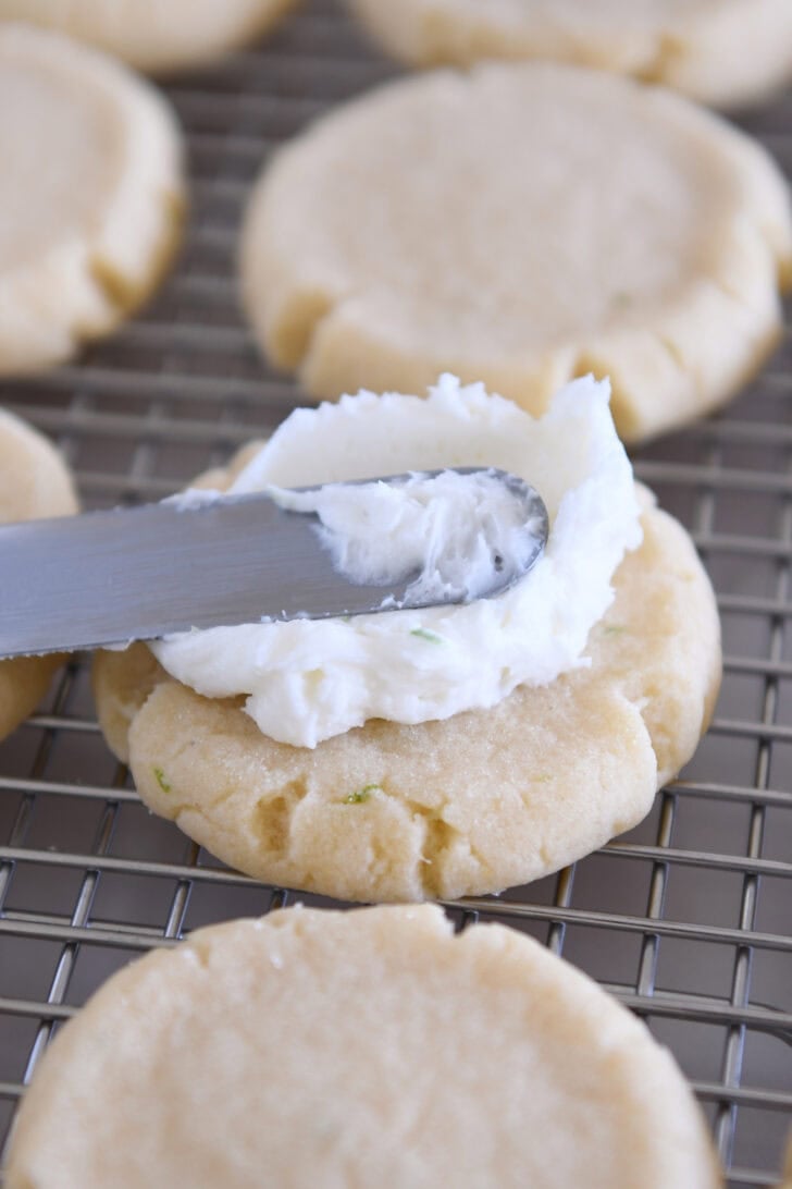 Frosting round sugar cookies with coconut lime frosting.