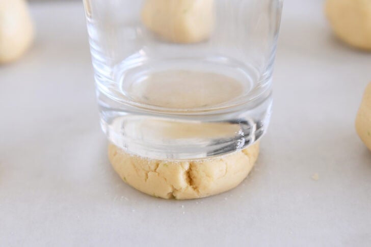 Roll the sugar cookie dough balls into a thick disk with a frosted soda glass at the bottom.