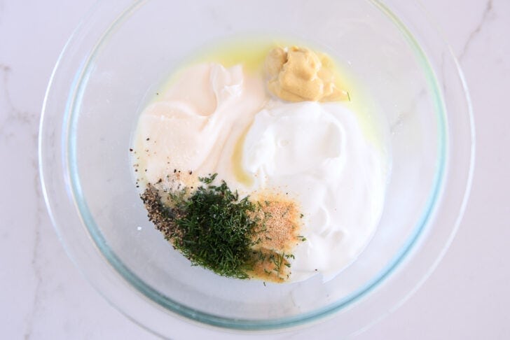 Glass bowl with mayo, greek yogurt, dijon mustard, dill, onion powder, black pepper and garlic powder.