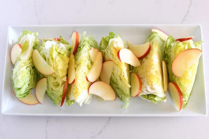 White platter with iceberg wedges and sliced apples.