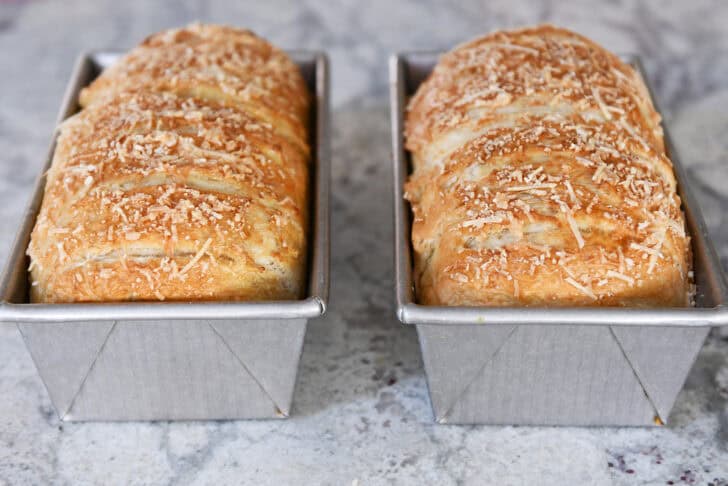 Two baked loaves of bagel bread dough in bread pans.