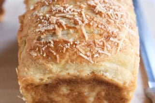 Baked loaf of bagel bread dough on wood cutting board.