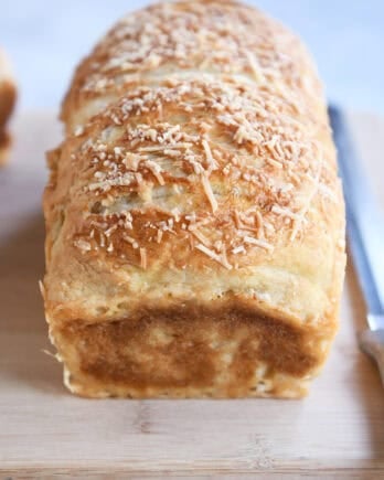 Baked loaf of bagel bread dough on wood cutting board.