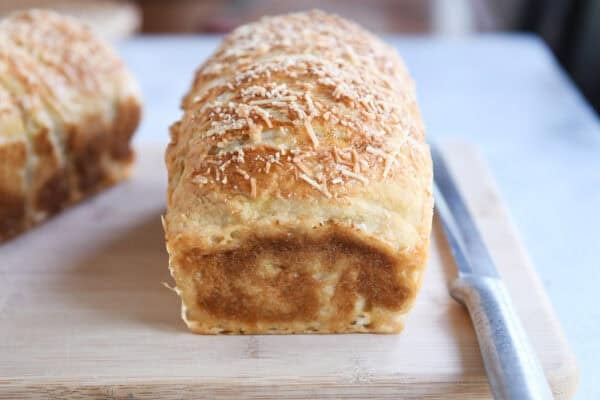 Baked loaf of bagel bread dough on wood cutting board.