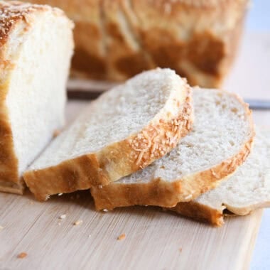 Three slices of bagel bread on wood cutting board.