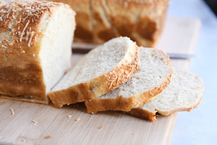 Three slices of bagel bread on wood cutting board.