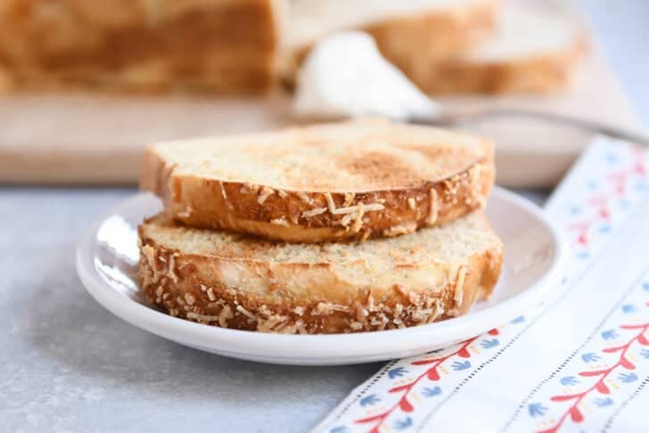 Two toasted slices of bagel bread on white plate.
