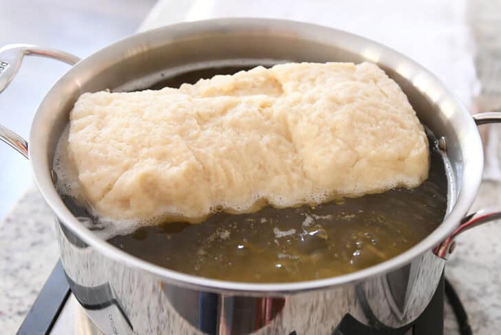 Boiling loaf of bread dough in large pot.