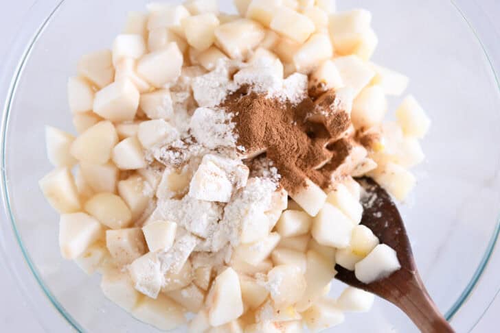 Glass bowl with diced pears, flour, and cinnamon.