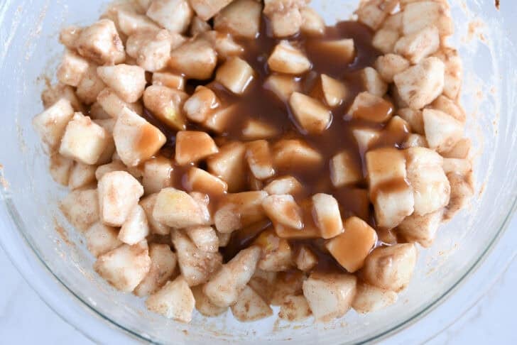 Glass bowl with diced pears, flour, cinnamon and caramel sauce.