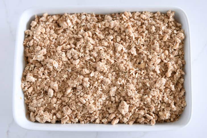 White 9X13-inch pan filled with unbaked caramel pear crisp.