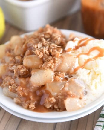 Double stack of white plates with serving of caramel pear crisp and vanilla ice cream.