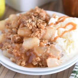 Double stack of white plates with serving of caramel pear crisp and vanilla ice cream.
