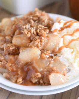 Double stack of white plates with serving of caramel pear crisp and vanilla ice cream.