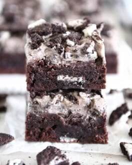 Two Oreo frosted brownies stacked on white parchment paper.