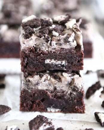 Two Oreo frosted brownies stacked on white parchment paper.