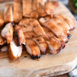 Wood tray with sliced pieces of grilled chicken.
