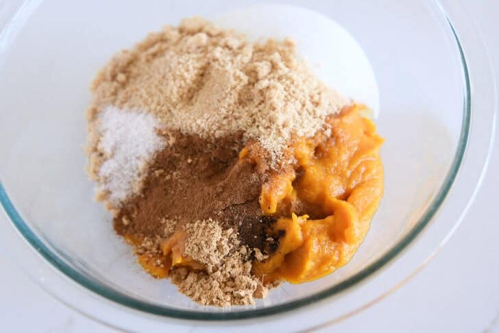 Glass bowl with canned pumpkin, granulated sugar, brown sugar, cinnamon and nutmeg.