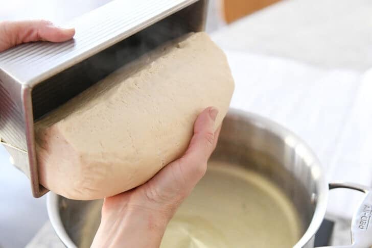 Turning out risen loaf of bread dough into hand.