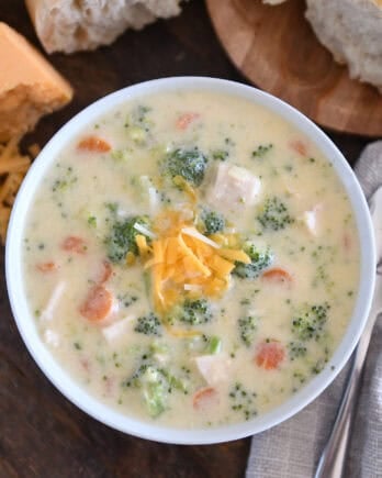Soup bowl with creamy soup, chicken, broccoli, carrots, cheese, and chicken.