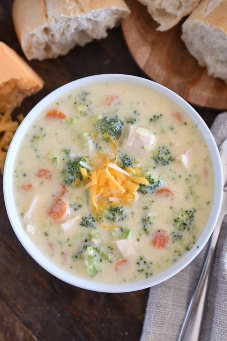 Soup bowl with creamy soup, chicken, broccoli, carrots, cheese, and chicken.