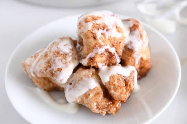 White plate with five cinnamon roll bites drizzled with icing.