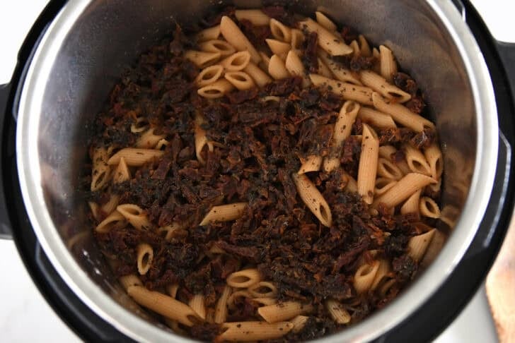 Instant pot with cooked pasta and sun-dried tomatoes.