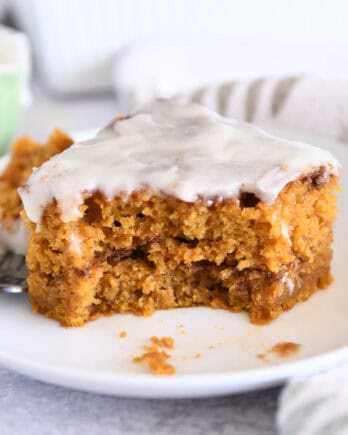 One square of pumpkin cinnamon swirl cake on white plate with bite taken out.