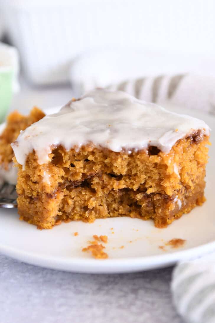 One square of pumpkin cinnamon swirl cake on white plate with bite taken out.
