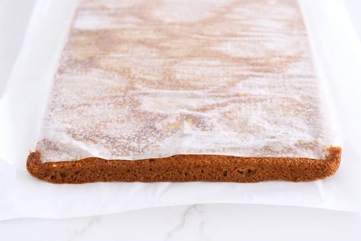 Parchment paper on over turned pumpkin sheet cake.
