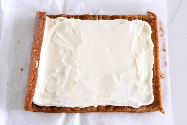 Pumpkin sheet cake starting to be rolled up with cream cheese frosting.