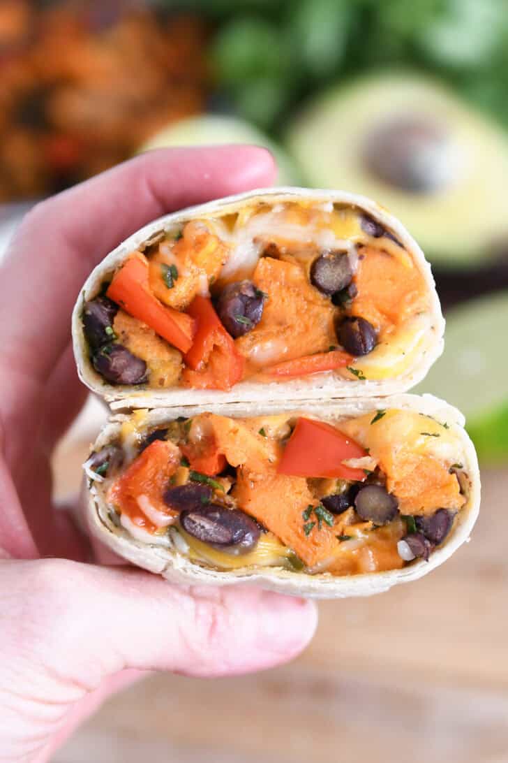 Two halves of sweet potato burritos held in hand.
