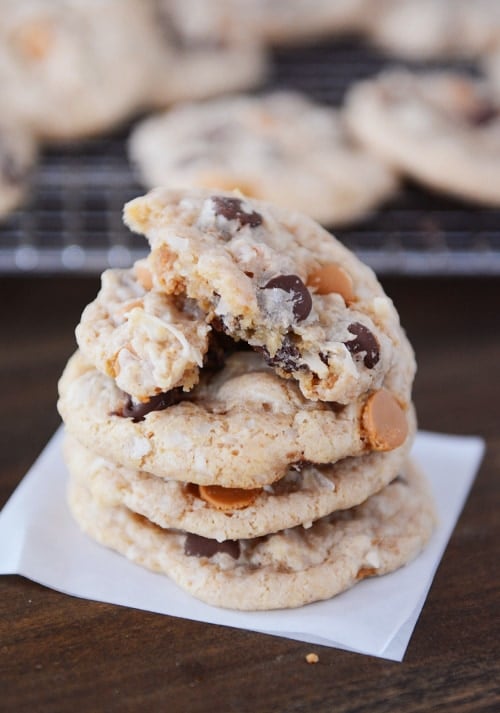 A stack of chocolate chip and butterscotch cookies with the top cookie split in half. 