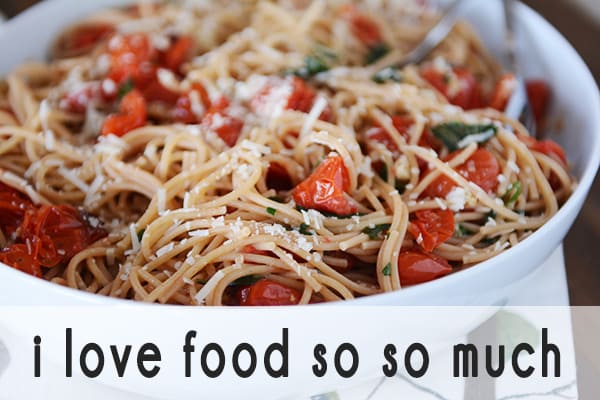 A bowl of cooked spaghetti noodles topped with diced tomatoes and parmesan cheese.