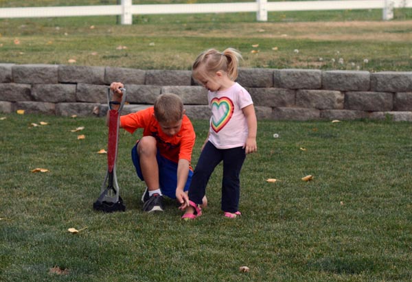 A little boy helping his sister put her shoe on.