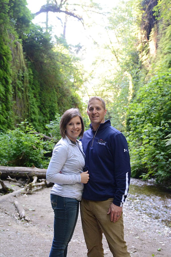 A man and woman standing in the forest.