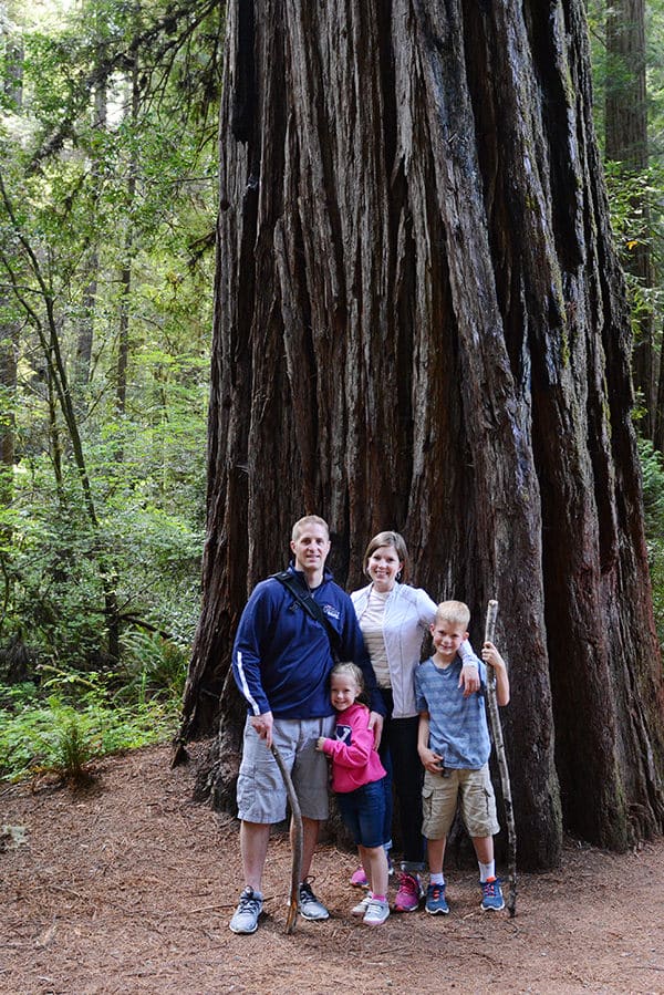 A Mom, Dad, and two kids standing in front of a large Redwood tree.