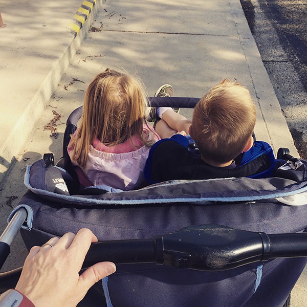 A little boy and girl in a jogging stroller.