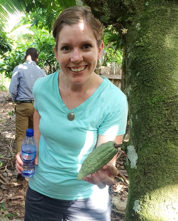 A woman holding a vegetable in one hand and a water bottle in another.