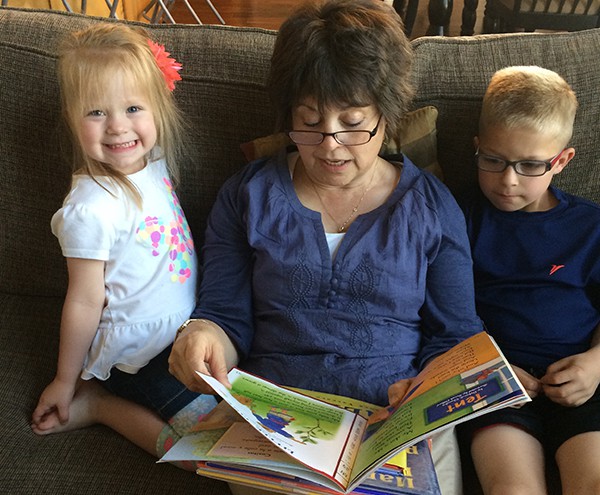 A grandma reading to a little girl and boy. 