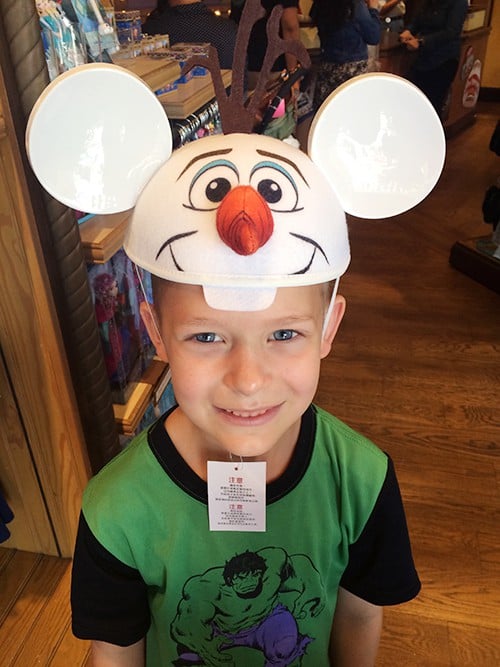 A little boy wearing an Olaf hat with mickey ears.