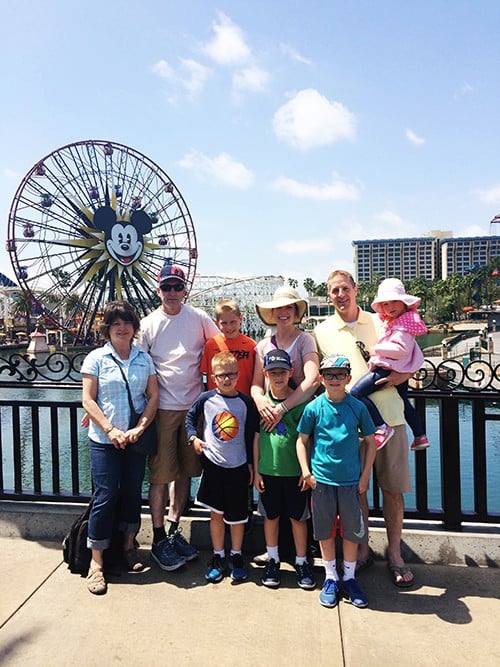 A family taking a picture in front of Mickey Mouse ferris wheel.